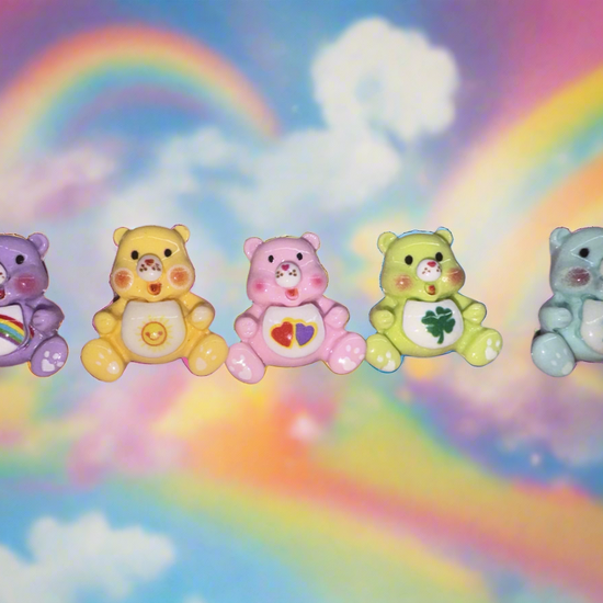 Colorful Care Bear nail charms set against a rainbow background, enhancing manicure style.