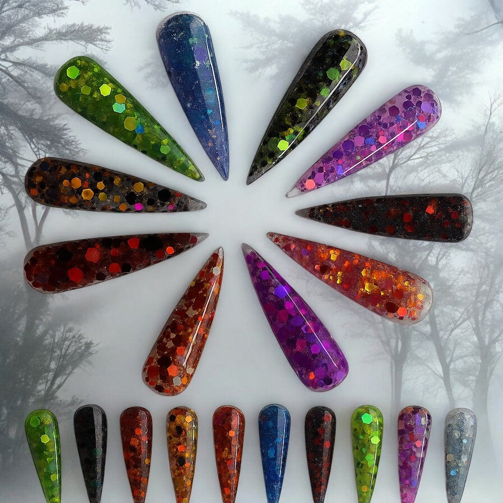 Halloween-themed long stiletto acrylic nails in various glittery colors including green, purple, red, orange, and blue arranged in a circle on a spooky forest background